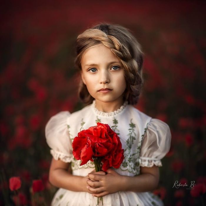Красивый портрет маленькой девочки с букетом ярко – красных маков.