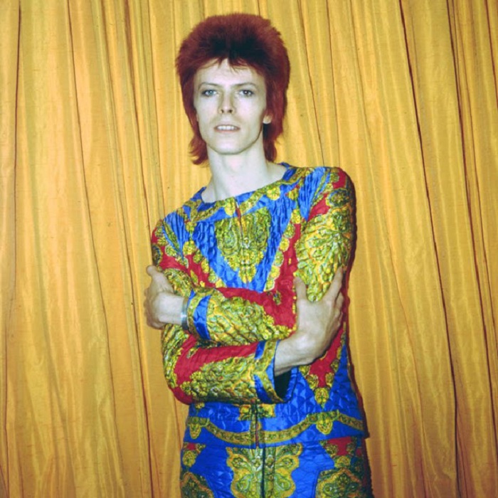 Легендарный певец в ярком стеганом костюме, созданном для тура «Ziggy Stardust» позирует в гостиничном номере в Нью-Йорке.