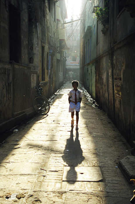 Учащийся школы возвращается домой после уроков по узким улочкам города.