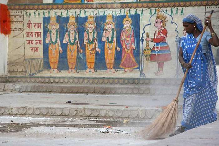 Женщина в голубом сари, наводящая чистоту на одной из улиц города Варанаси.