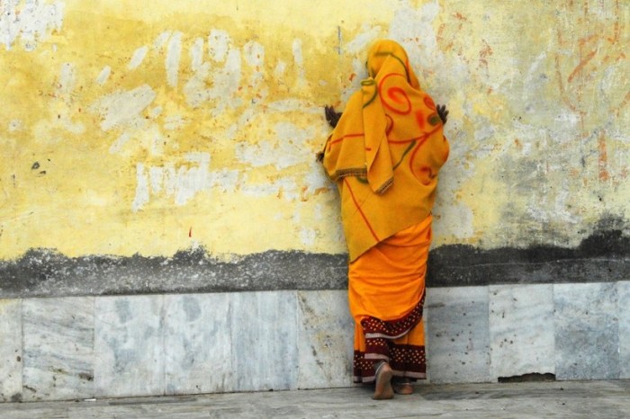 Молящаяся женщина возле стены храма в Орчхе во время духовного праздника.