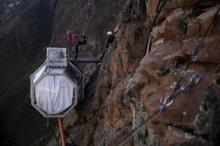 Туристы поднявшиеся с помощью железного троса на вершину скалы, чтобы провести ночь в прозрачной палатке.