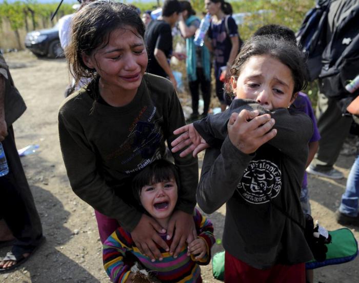 Девочки плачут из-за того, что их разлучили с семьей на границе Македонии и Греции.