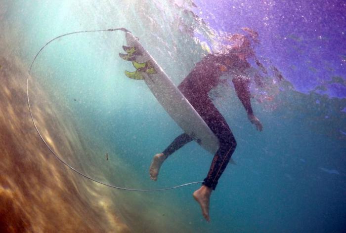Серфер Арлен Макферсон демонстрирует доску для серфинга, оснащенную электронным отпугивателем акул на пляже Бонди Бич.
