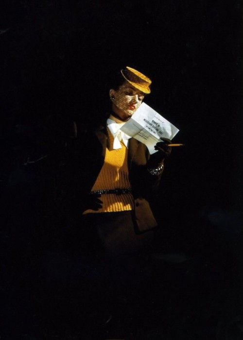 Модель в желтой шляпке с вуалью и свитере, декорированном широким бантом.