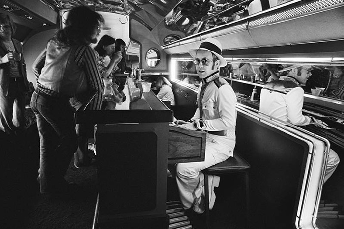 Элтон Джон за пианино-баром на борту его личного самолета, 1976 год.