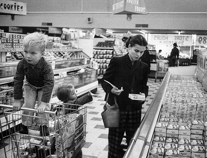 Молодая мама с двумя детьми покупает продукты. 1956 год.