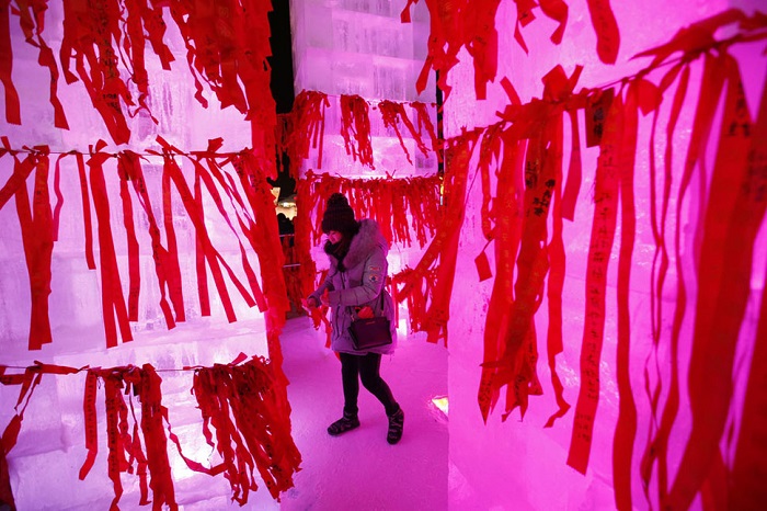 Посетители завязывают красные ленты с желаниями на открытии международного фестиваля.