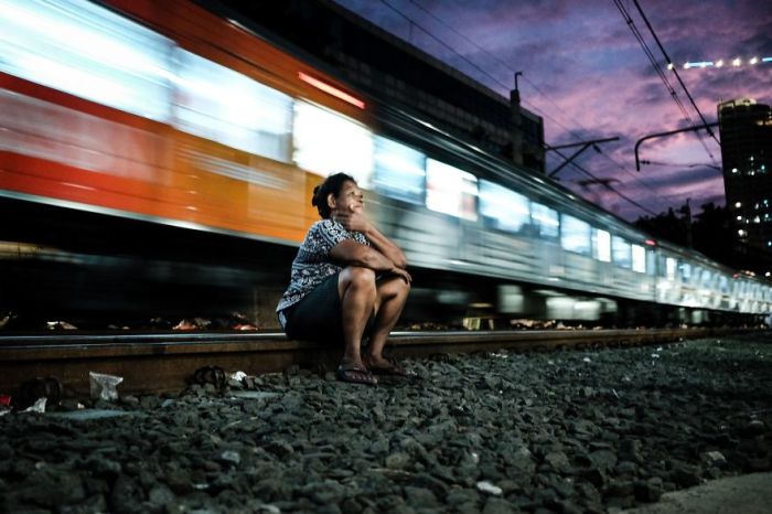 Женщина отдыхает на рельсах под стук проносящегося позади нее поезда.