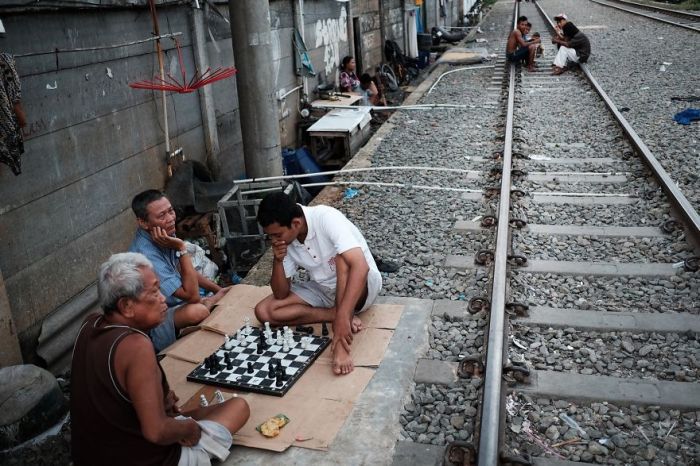 Мужчины играют в шахматы вблизи с железнодорожными путями.