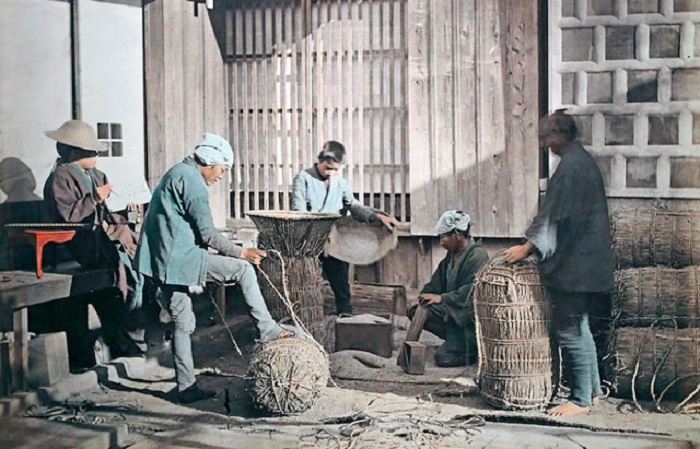 Рабочие закатывают рисовые тюки для продажи.