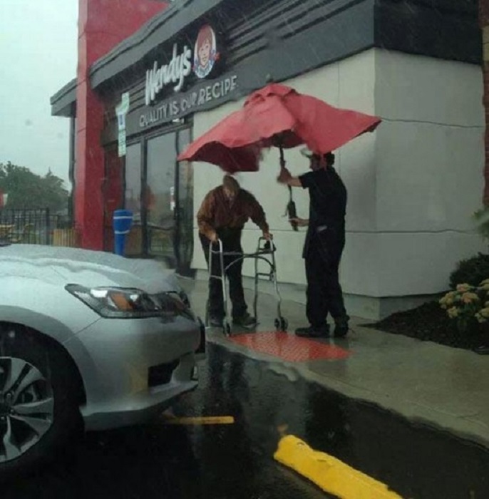 Работник ресторана Wendy’s взял зонт со столика, чтобы проводить пожилого мужчину до машины в сильный дождь.