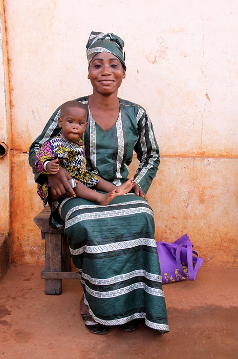 Мама в традиционной одежде позирует фотографу с сыном на руках.