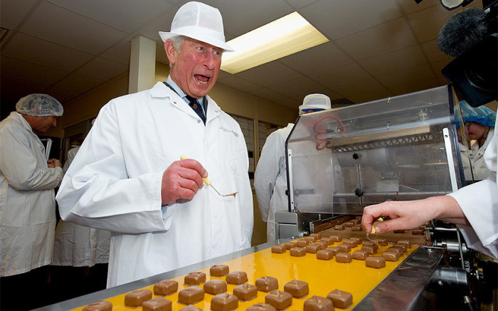 Принц Чарльз украшает шоколад во время официального визита на фабрику.
