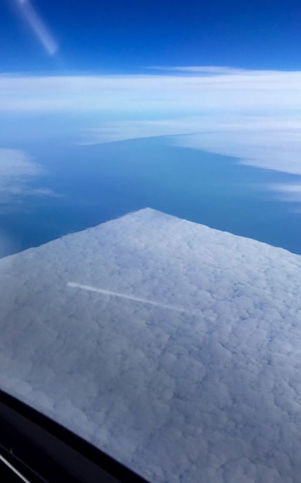 Фотография квадратных облаков сделана из иллюминатора самолета.