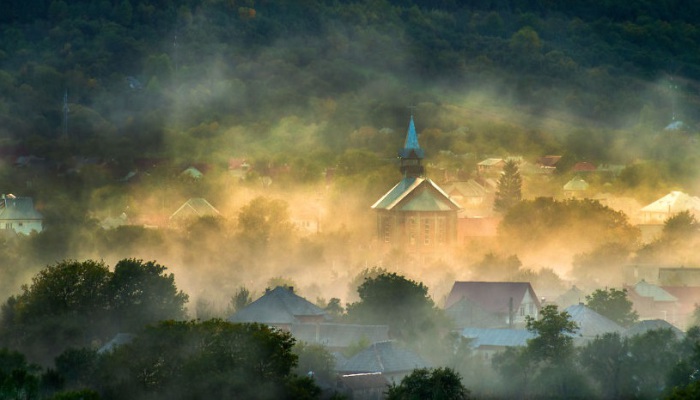 Небольшое поселение в горах, окруженное утренним туманом.