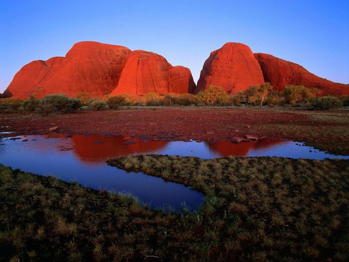 Огромные красные горные купола неожиданно возвышаются прямо из австралийской пустыни, одновременно вызывая чувства страха и восхищения.