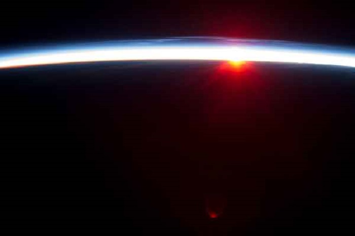 Тонкая линия земной атмосферы и заходящее Солнце.
