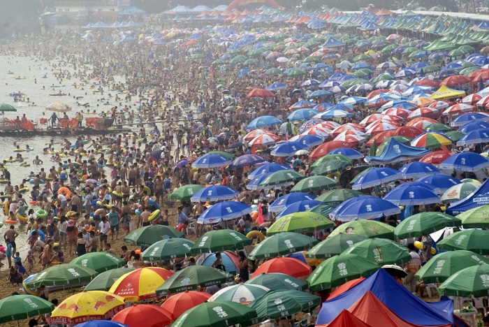 Люди толпятся на пляже в городе Далянь, провинция Ляонин, спасаясь от летней жары.