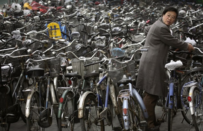Женщина забирает свой велосипед на стоянке за станцией метро в Пекине.
