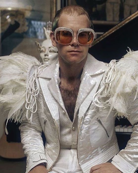 Британский певец и композитор в белом сценическом костюме, декорированном перьями и пайетками (1973 год).