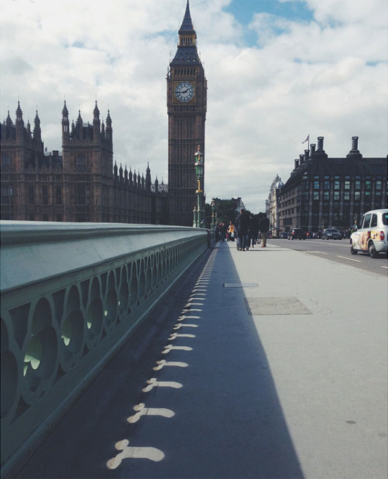 Часовая башня Вестминстерского дворца в Лондоне бросает тень на мостовую.