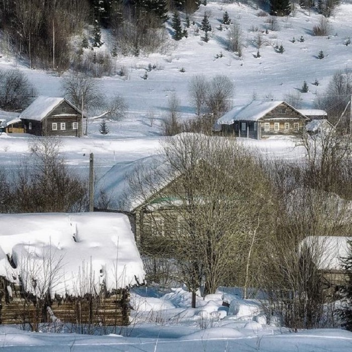 Сонные деревянные домики русской деревни, заметенные снегом.