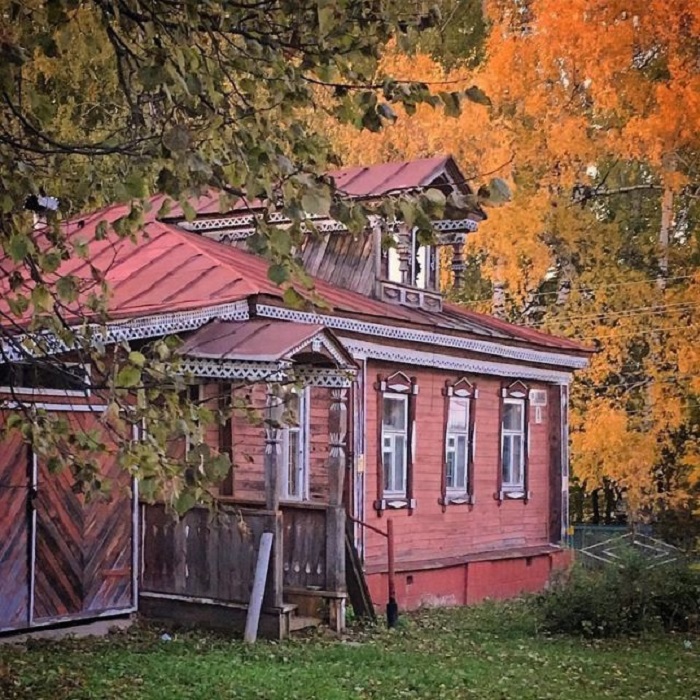 Деревенский домик с резным крыльцом не уступает яркостью красок осенним деревьям.