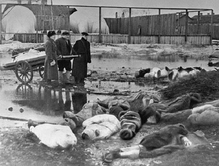 Трое мужчин хоронят жертв блокады Ленинграда.