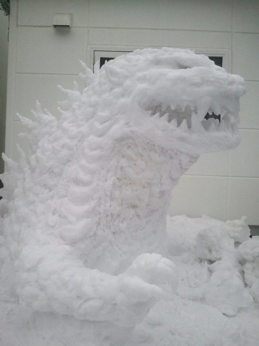 Небольшой, но довольно детализированный доисторический ящер-монстр Годзилла из снега расположился в одном из дворов.