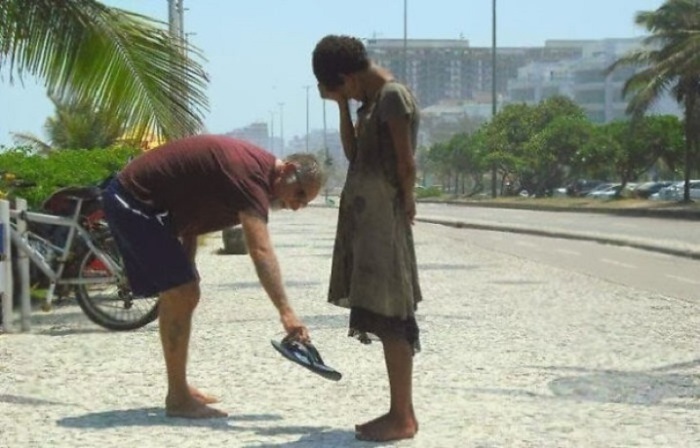 Человек, дающий свою обувь бездомной девочке в Рио-Де-Жанейро.