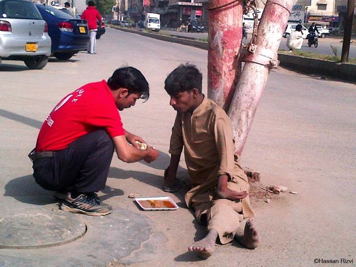 Официант покупает еду и кормит инвалида в Карачи, Пакистан.