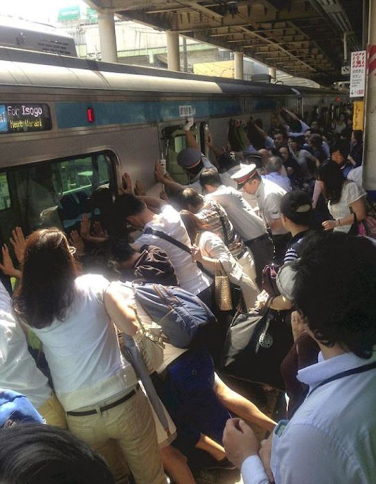 Люди вместе поднимают поезд, чтобы спасти человека, застрявшего между вагоном и платформой.