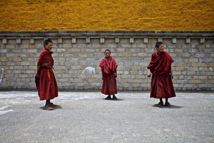 Мальчики, играющие возле храма Ганден Тубчен Чоххорлинг, внимательно слушают учителя, который вышел вернуть их в монастырь.