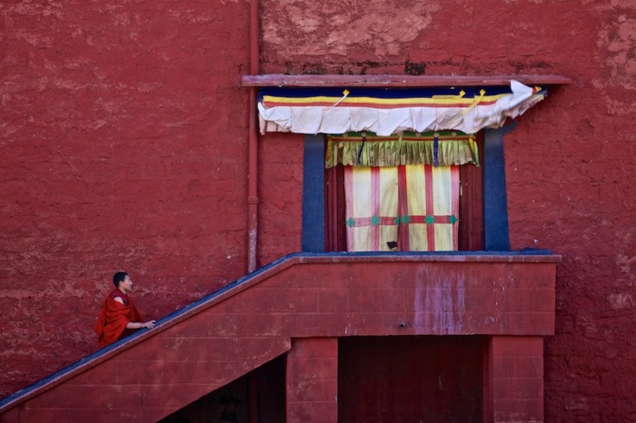 Монах направляется к черному входу храма с красочными стенами, основанного третьим Далай-ламой Сонамом Гьяцо в 1580 году, для проведения молитвы.