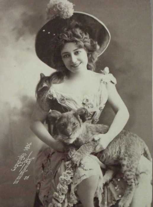 Старый снимок девушки, которая держит львенка на руках.