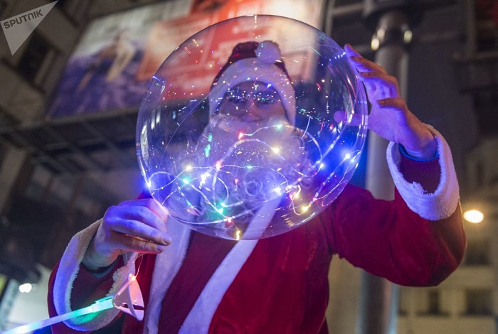 Мужчина в костюме Деда Мороза с праздничным надувным шариком.