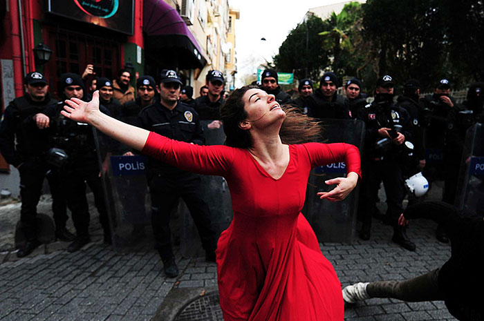 Женщина, танцующая перед сотрудниками спецподразделения полиции во время демонстрации против выселения.