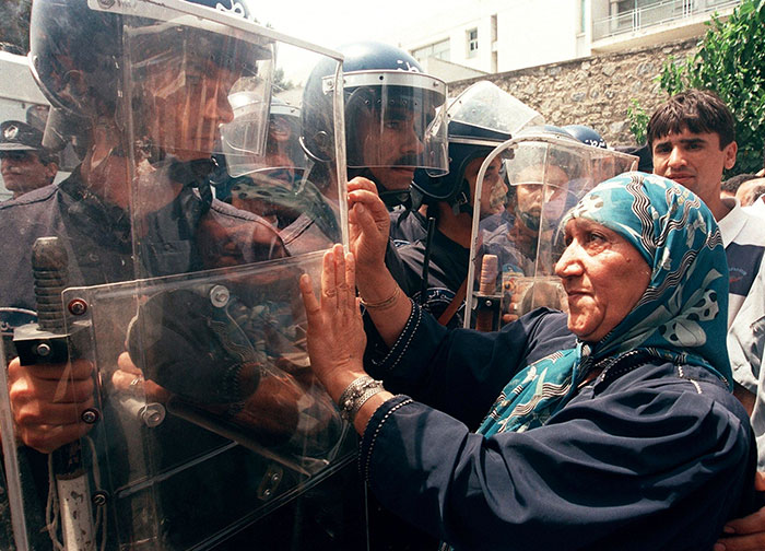 Женщина пытается жестами остановить полицейских во время демонстрации, собравшейся в знак протеста против нового закона, признававшего арабский единственным официальным языком страны.