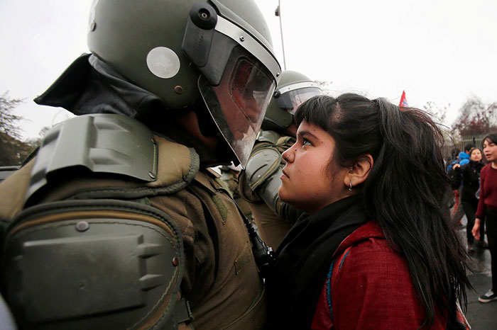 Девушка смотрит в глаза сотруднику специальной полиции во время демонстрации, приуроченной к годовщине военного переворота 1973 года.