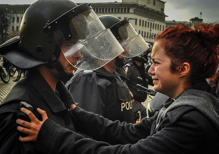 Плачущая девушка просит полицейского не использовать силу против людей, вышедших на акцию протеста против экономической политики властей.