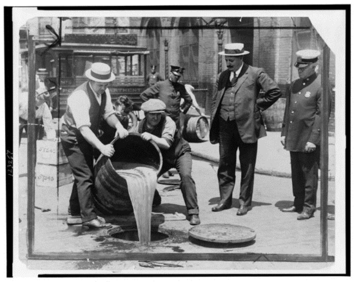 Нью-Йорк, 1921 г. Заместитель комиссара полиции Джон А. Лич наблюдает, как конфискованный ликер выливают в канализацию
