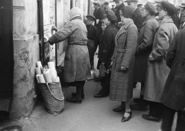 Люди, читающие только что расклеенные женщиной плакаты. СССР, Москва, 1935 год.