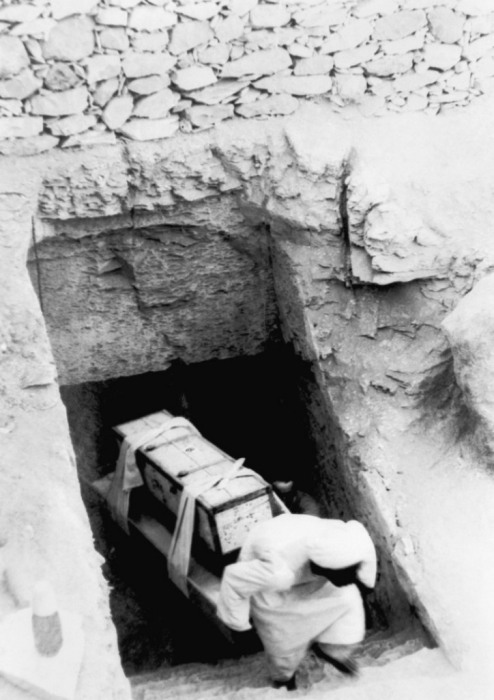 Вынос рабочими древних артефактов и сокровищ из гробницы фараона во время раскопок в Каире.