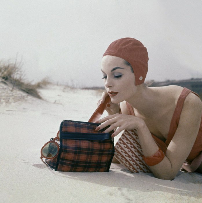 Девушка, достающая из сумки расческу на пляже. 1950-е годы.
