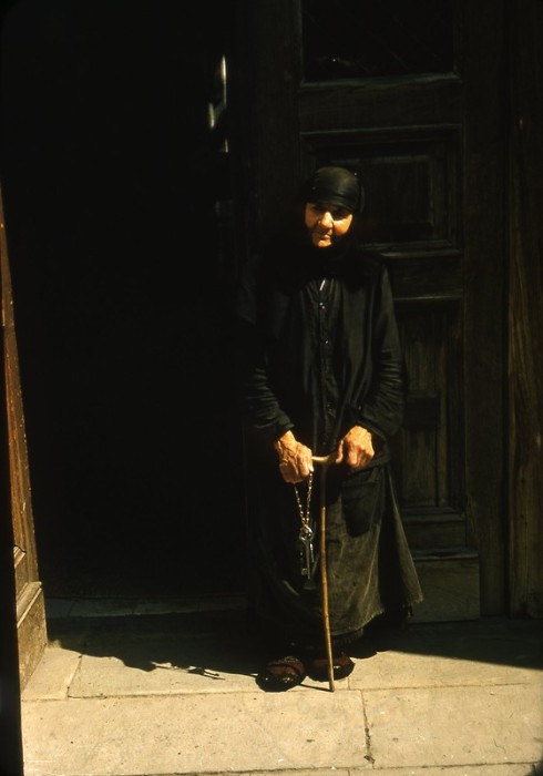 Пожилая монахиня у входа в православный храм.