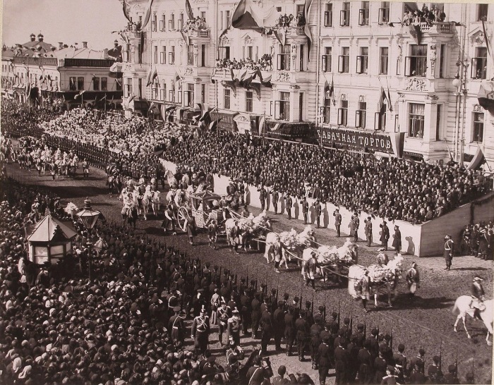 Коронационная карета императрицы Александры Федоровны проезжает мимо трибун со зрителями от Триумфальных ворот по Тверской улице.