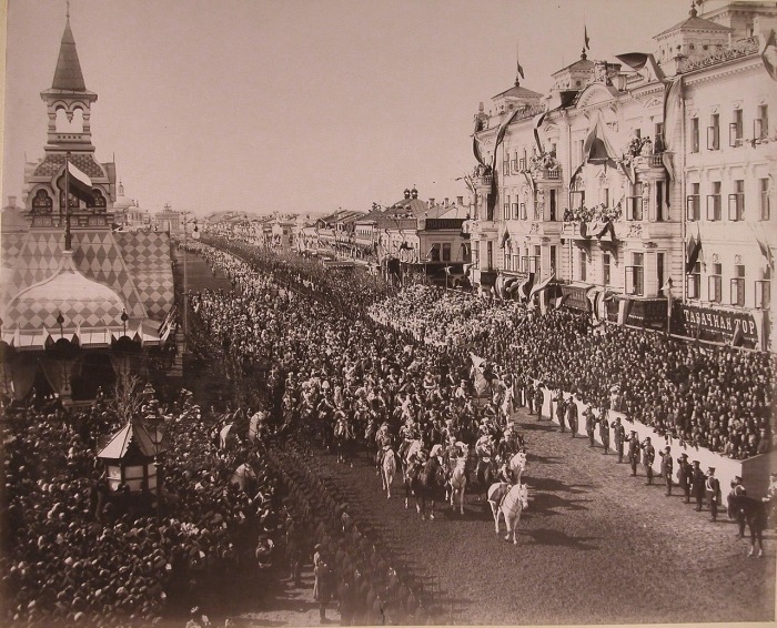Император Николай II в сопровождении свиты шествует перед трибунами от Триумфальных ворот по Тверской улице.