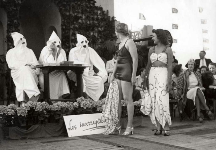 Две дамы в купальниках проходят мимо трёх представителей ультраправой организации ку-клукс-клан во Франции в 1937 году.