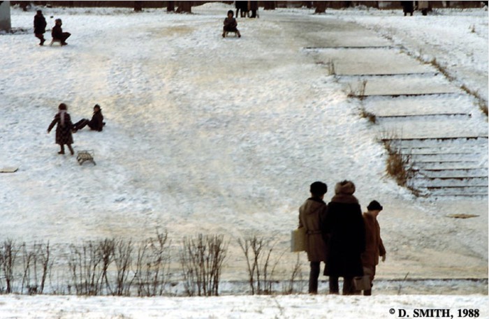 Дети, катающиеся на санках по склону холма. СССР, Москва, 1988 год.